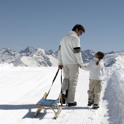 Vater mit Tochter beim Schlittenfahren