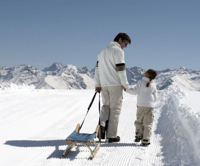 Vater mit Tochter beim Schlittenfahren